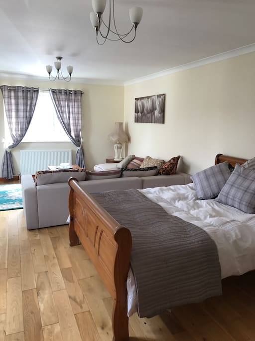 Large open plan area featuring king size bed and sitting area