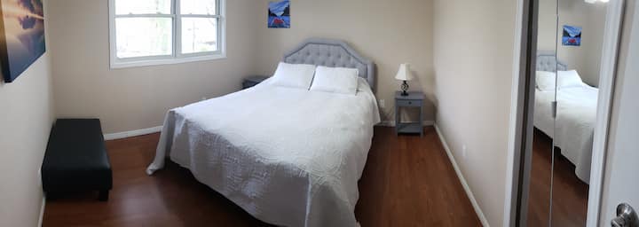 Upper level bedroom with queen bed , end tables , bench, closet ceiling fan and table lamp.