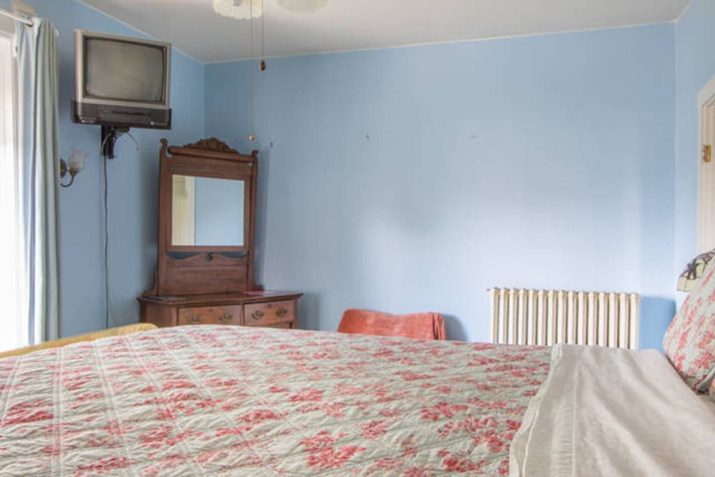 The blue room has a dresser and small sitting chair. If needed there is another mattress stored under the bed.