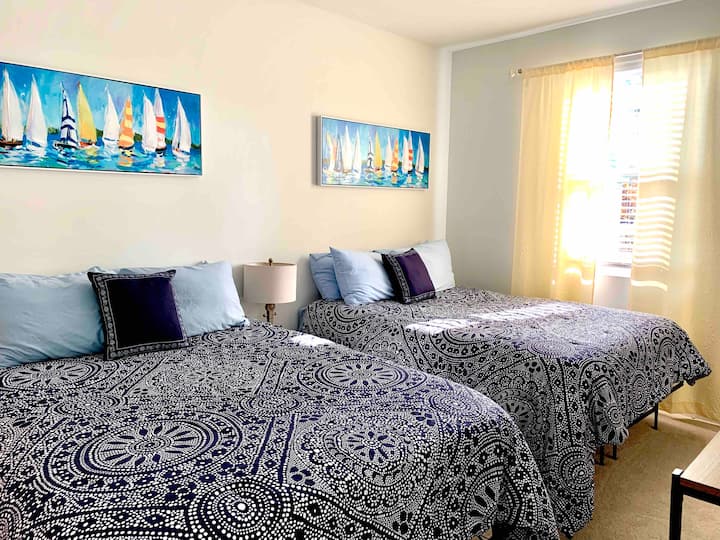 Dormitorio #2. Dos camas tamaño queen con vestidor y TV.  Baño compartido en el pasillo