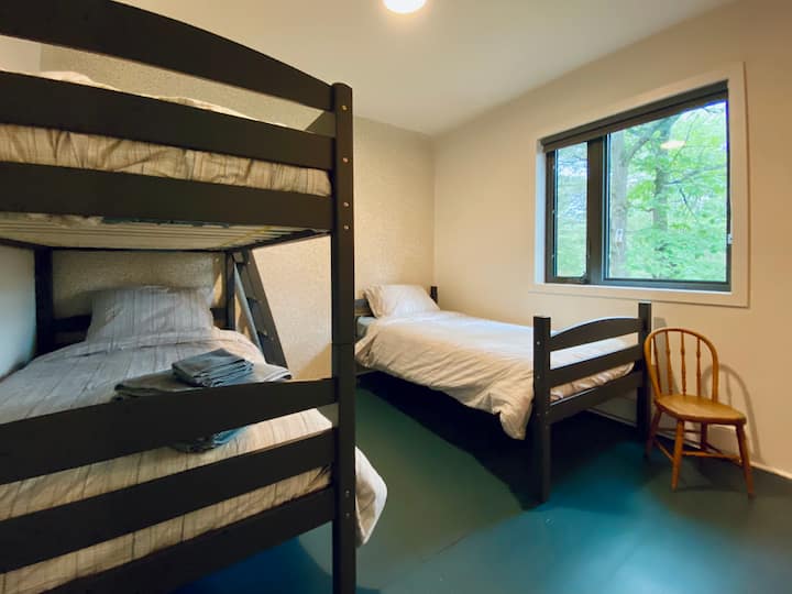 The bunk room has 3 twin beds and a collection of children's books.