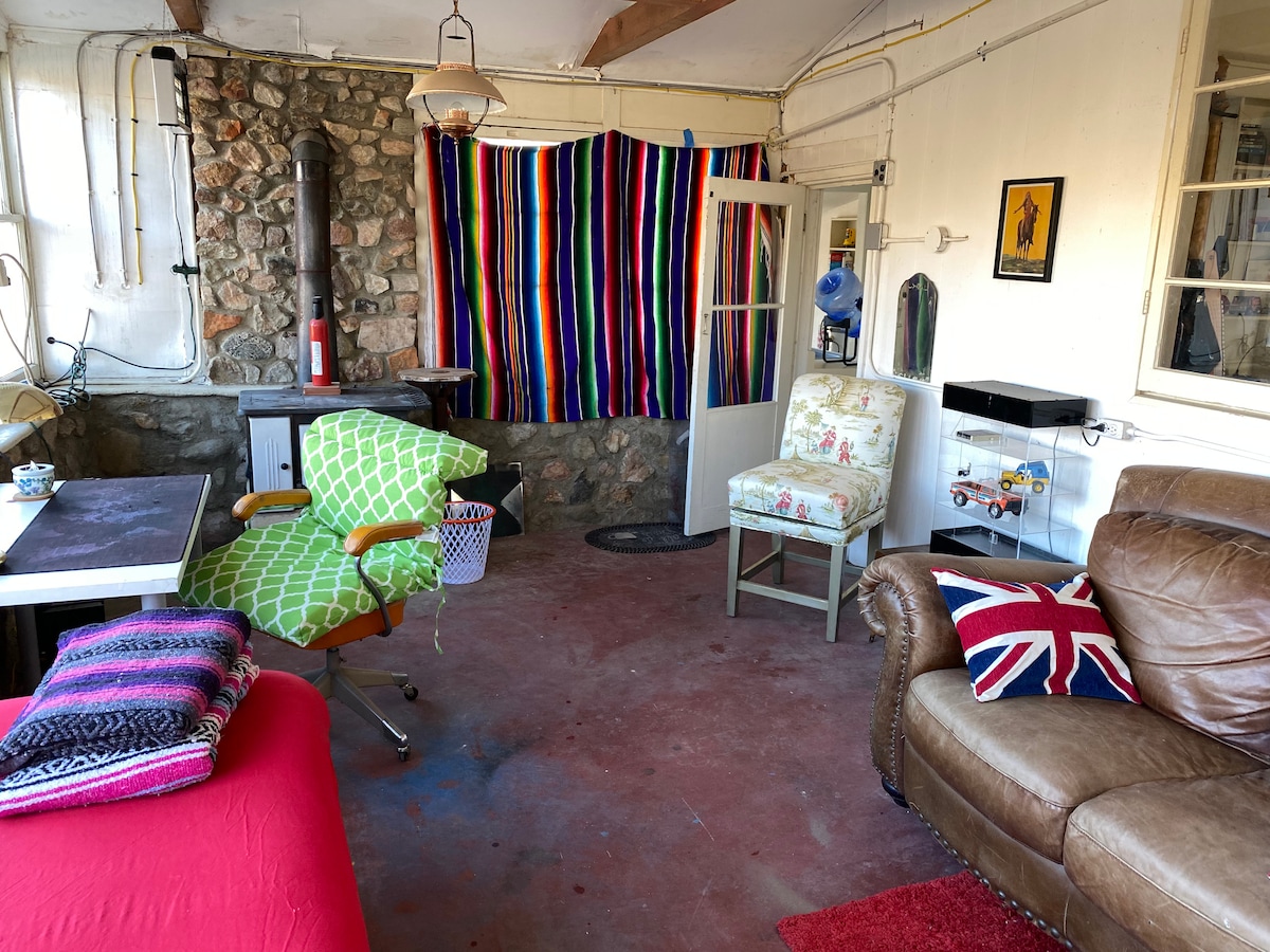 Red sunroom, equipped with an office desk and a wood burning vintage stove as well as an amazing view of the desert landscape.