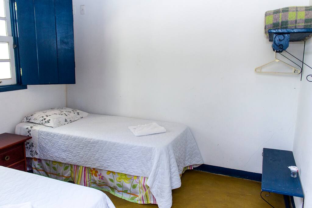 Quarto com duas camas box, de solteiro. Detalhe do espaço para roupas e malas