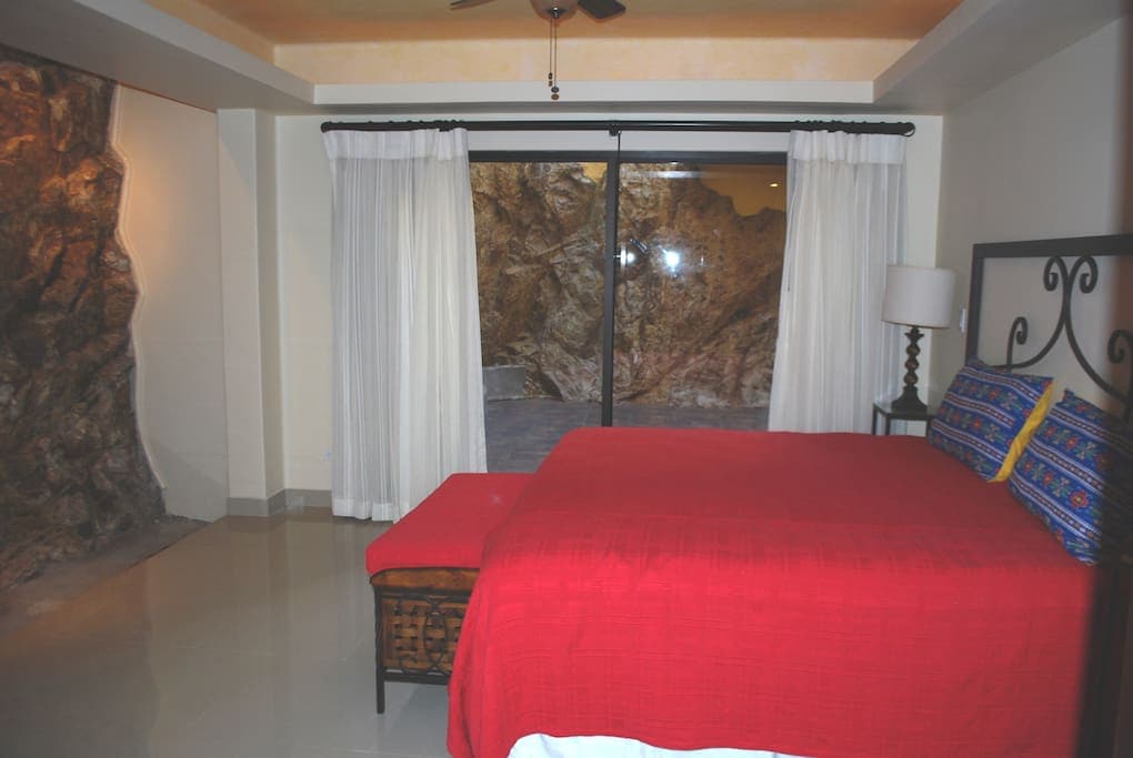 Bovenslaapkamer met natuurlijke rotswand. Eigen patio met waterval.