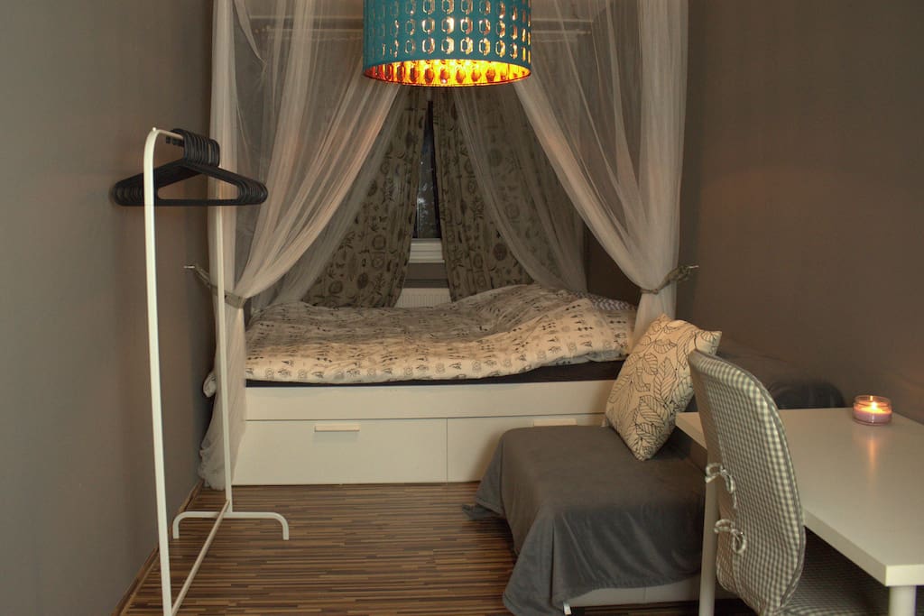 Das Gästezimmer mit Kleiderstange, Arbeitsplatz, Sitzgelegenheit, kleinem Regal (links, nicht im Bild) und Doppelbett.
