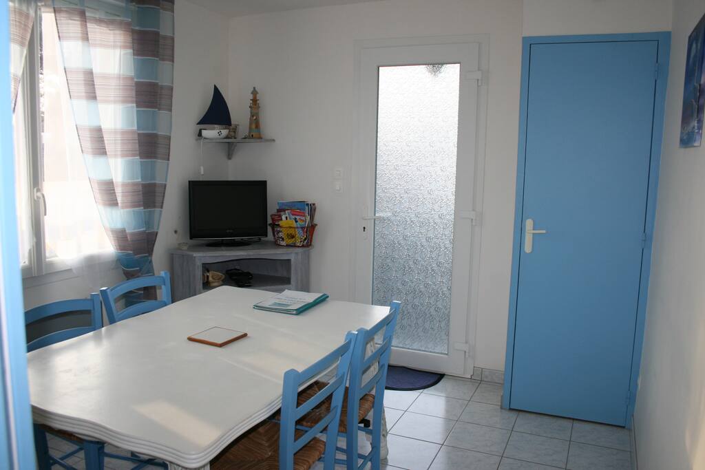 Coin repas avec télévision TNT, jeu de société, documentation sur la région, placard avec aspirateur et nécessaire de nettoyage.
