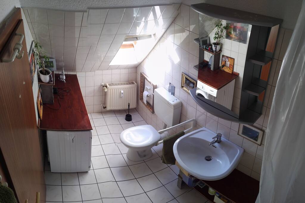 Badezimmer mit Toilette, Waschmaschine, Waschbecken und Dusche/Badewanne