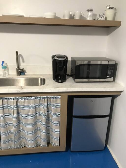 Keurig K-cup coffee maker, microwave, refrigerator, there is also a kitchen aid convection/toaster oven behind curtains.