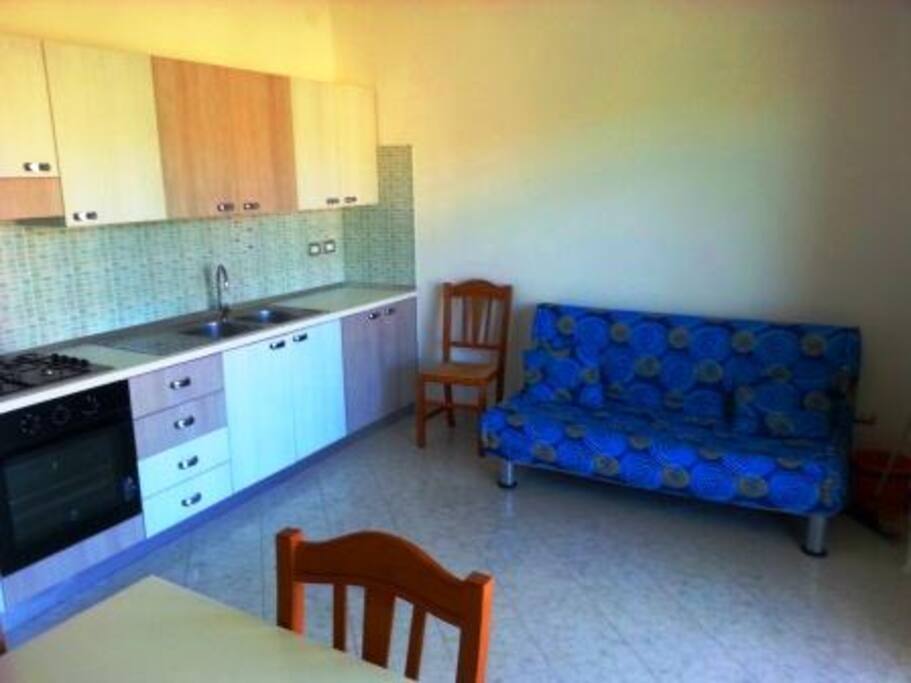soggiorno con divano letto matrimoniale e angolo cottura