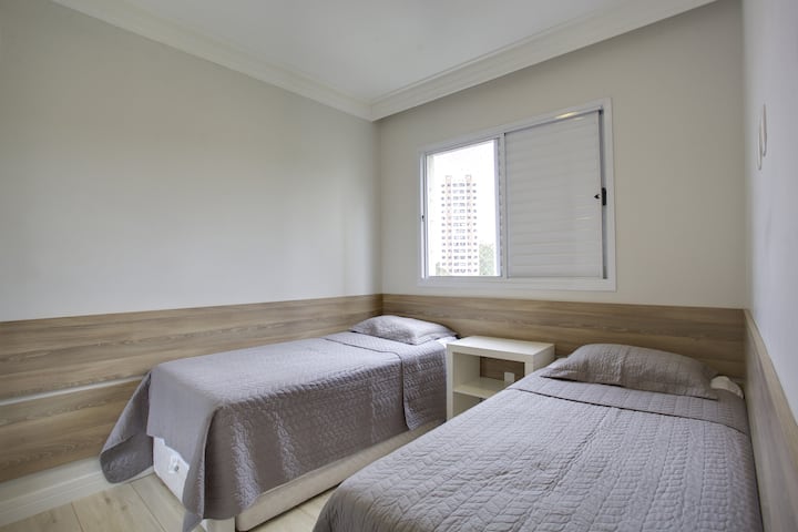 غرفة نوم مع 2 سرير مربع واحد وخزانة مع باب مرآة.