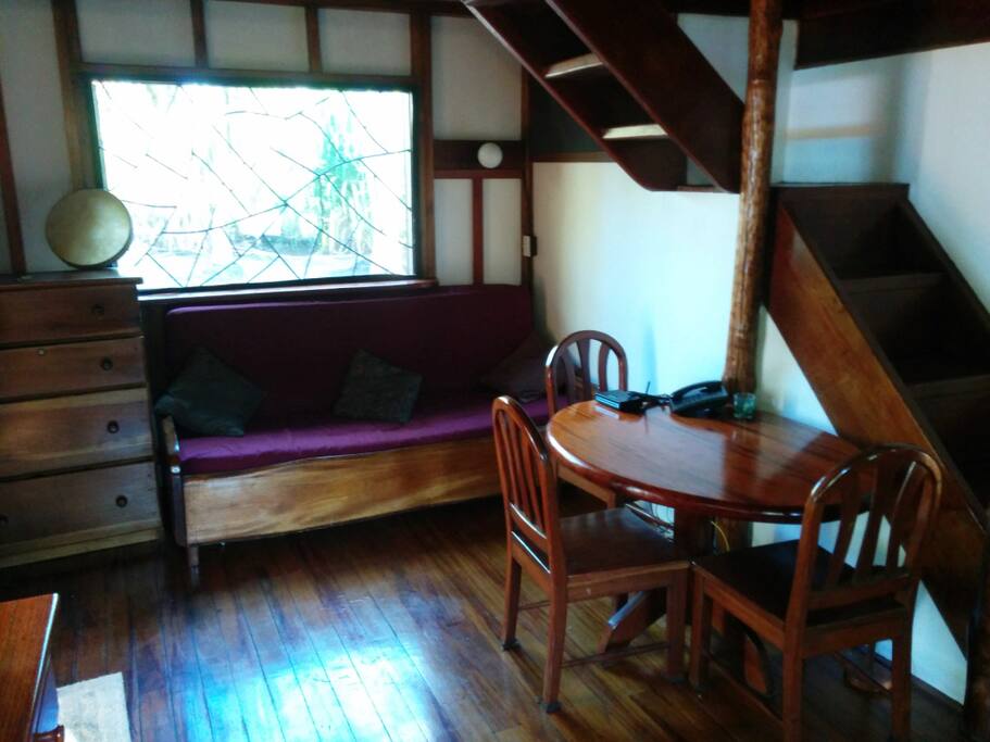 Living room with stairs going to top floor. The stairs now have a railing.