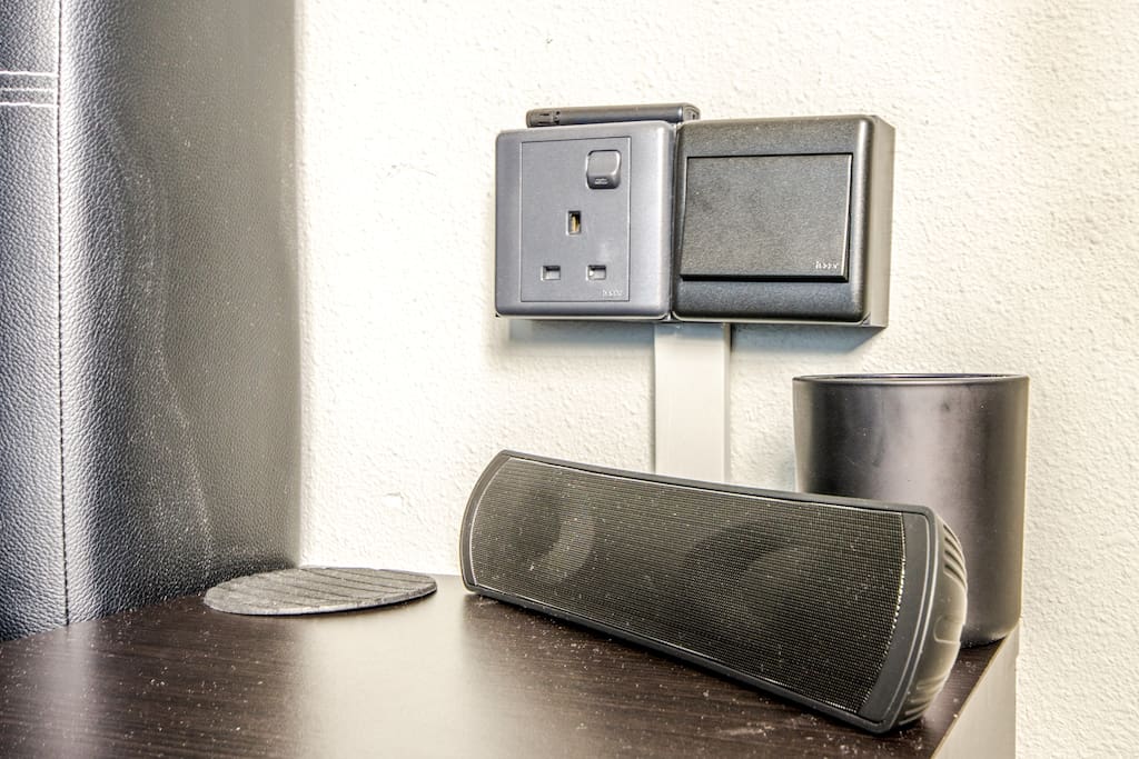 Bluetooth speaker, scented candle atop bedside table