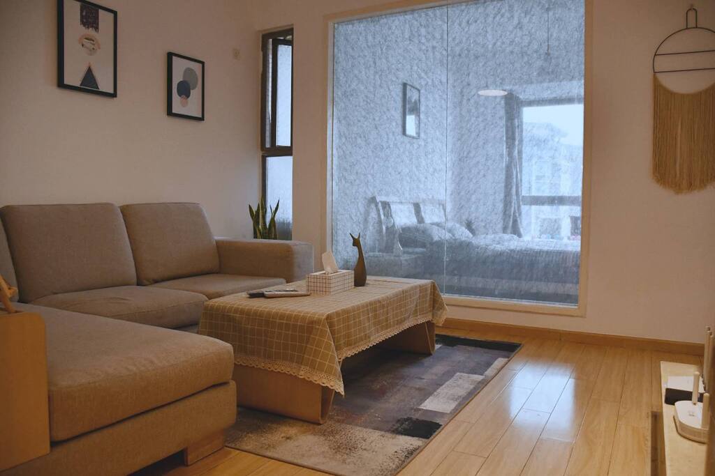 原木亮色挂画装饰的沙发背景墙,配合布艺沙发,使得整个客厅既时尚又舒适。