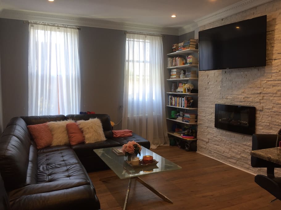 High end and cozy living room area with views of Washington Street, an electric fireplace, central heat, small library and TV.