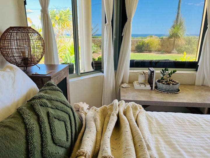 Dormitorio frente a la playa. Cama tamaño queen, ventanales con vistas al mar. Aire acondicionado de ciclo inverso. 
Puerta corrediza de vidrio, el acceso principal a Airbnb.  