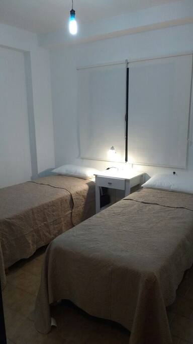 Habitación con dos camas sommier con colchón canon individuales que pueden juntarse y formar una cama matrimonial, mesa de luz, espejo de cuerpo entero con lampara comun, placar con cajonera y perchas, ambiente luminoso con ventana de 1,50 x 1.80 con persianas que provocan total oscuridad, sabanas cubrecamas, almohadas y frazadas muy confortable.