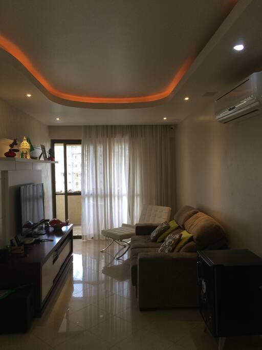 Sala confortável com sofá, mesa para 6 lugares e tv de 65'
