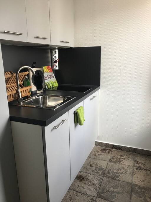 Côté cuisine avec plaques, hotte. Frigidaire encastré. Machine Dolce Guisto et nombreux placards.