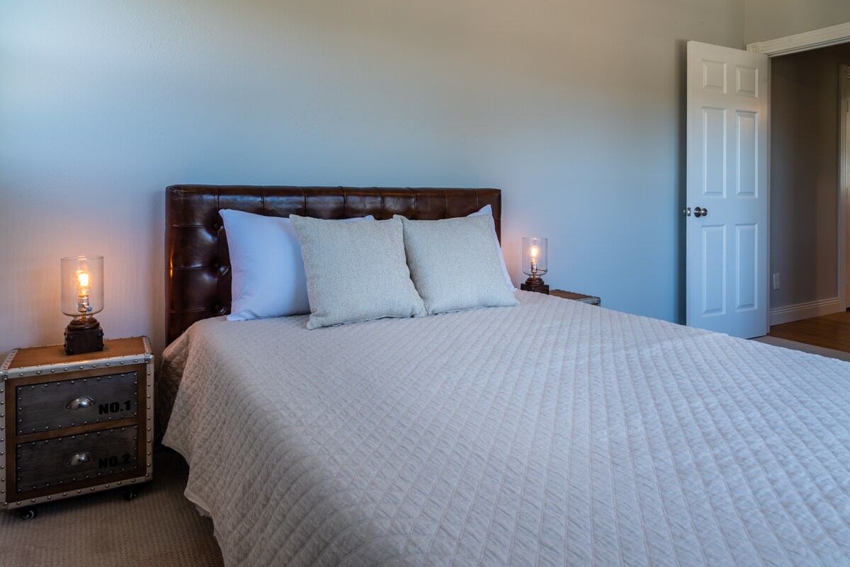 Dormitorio uno en la planta principal con una cama tamaño queen cerca de un baño en el pasillo. 