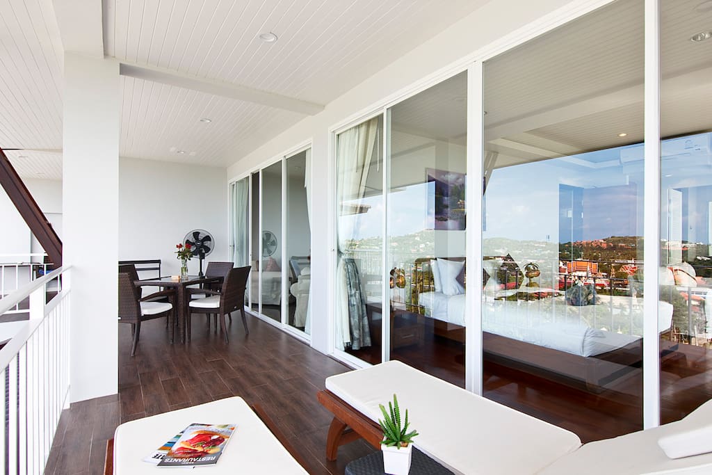 Large front balcony with outdoor furniture setting and sunbeds