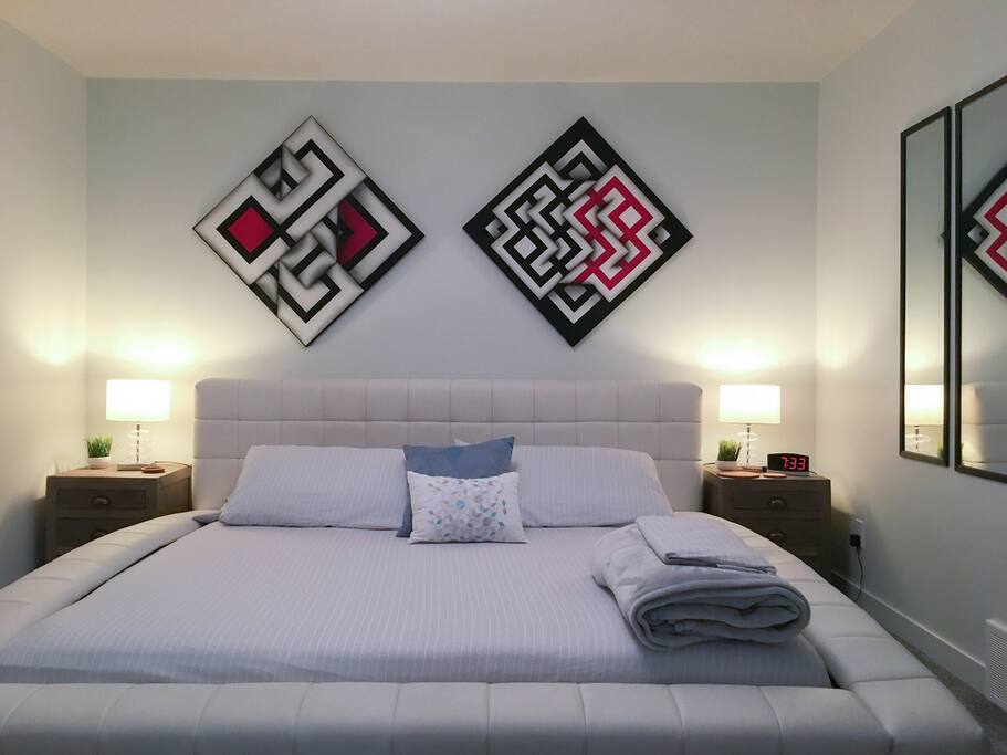 King size platform bed with high end mattress, room decorated with optical art paintings.