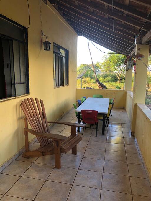 Varanda com cadeira de descanso, e mesa com 10 cadeiras infantis