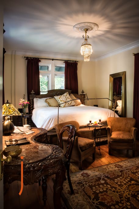 Elegant king size bed in the Meyer Room at the JL Mott Mansion has subtle touch controlled LED lighting, carved wooden furniture, QLED 55" surround sound movie system.
