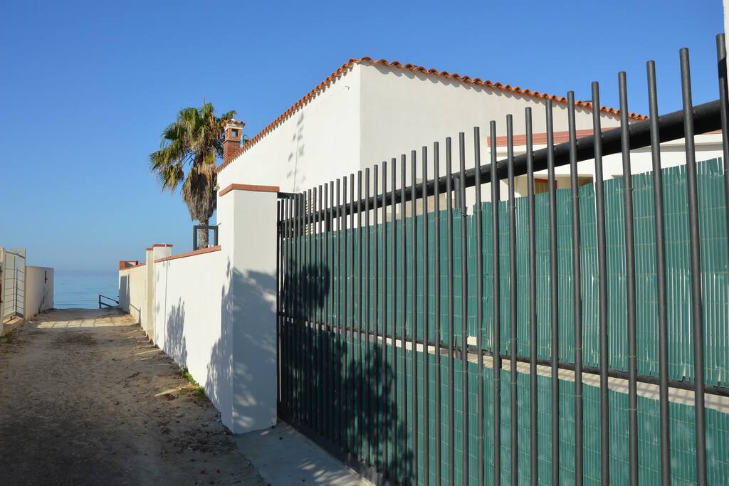 Ingresso di Villa Luna: il cancello, la palma e il mare . La stradina che porta a Villa Luna sul Viale Windsurf.