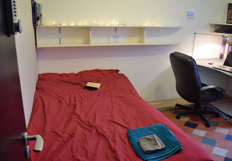 shows the bed, shelving, armchair, desk and door with digital lock.