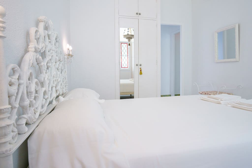 The bedroom has 11m2, a queen size bed, a closet and a coquette with a white marble top. Painted in white and with high ceilings. Triple glazing, stained glass windows and solid wood shutters give access to a balcony overlooking Antonio Lopez Street. Softly illuminated by an old votive lamp suspended from the ceiling and light fixtures on two carved brackets that serve as bedside tables. Towels & linen are provided.