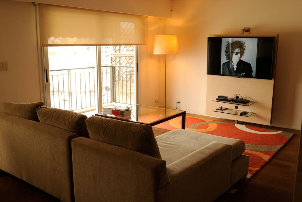 Living con salida al balcón con plasma y sillón de 3 cuerpos
