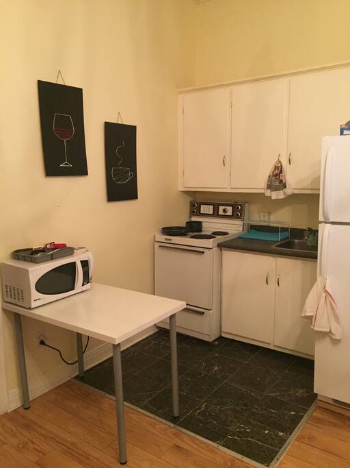 Kitchen with all necessary utensils - microwave, fridge, pots and pans, plates and glasses, cutlery.