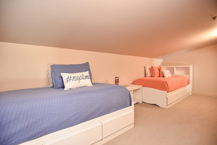 小阁楼区域后卧室（两张单人床，带脚轮储物柜和拱形天花板）。适合儿童入住。