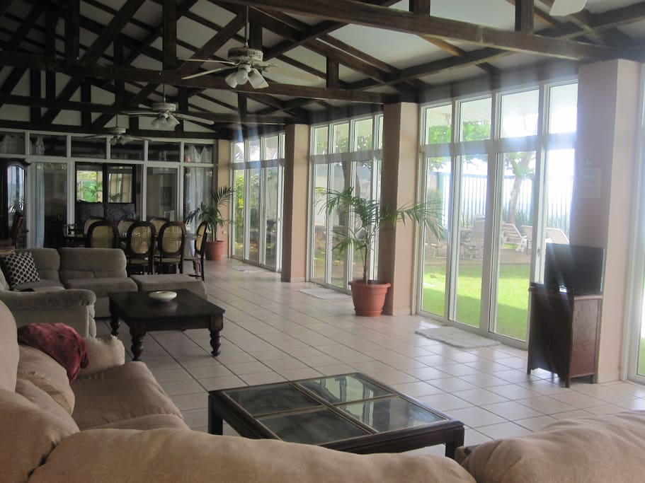 Glassed living area with 2 sectional sofa & 2 eating areas facing pool & ocean