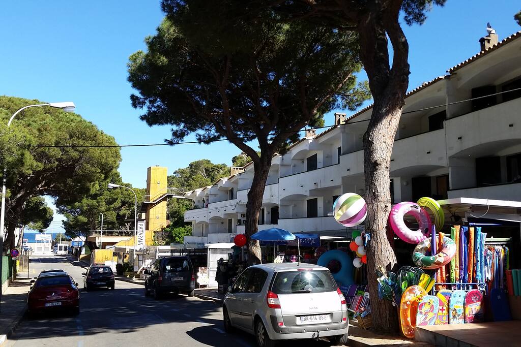 Apartment on second floor partly hidden by pine-tree in the foreground/Seaside down the street