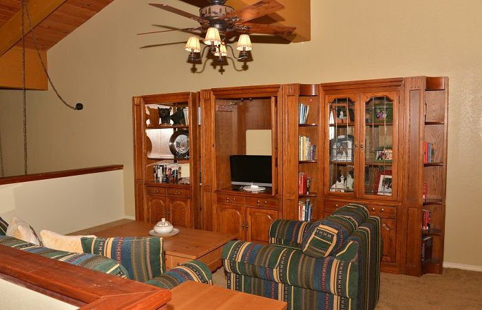 Potkrovlje s TV-om, kaučem za spavanje i stropnim ventilatorom.