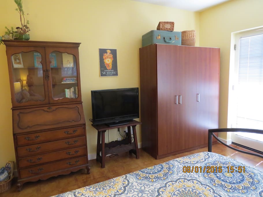 Living space with HDTV, writing desk, and large wardrobe
