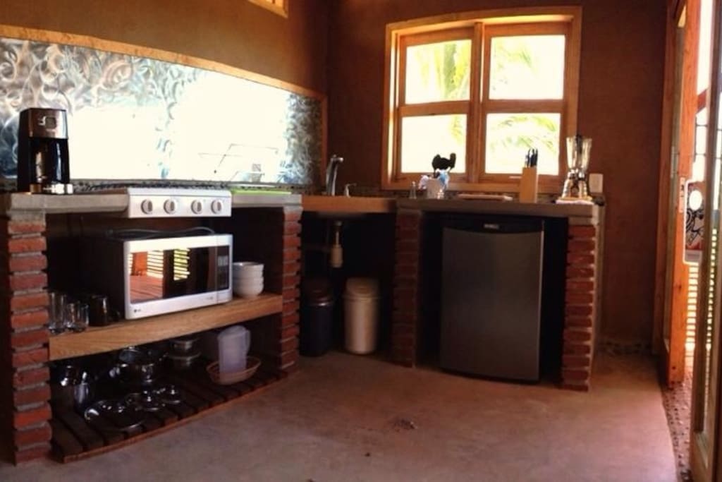 Kitchenette with fridge, coffee machine, blender, microwave, gas stove and more.