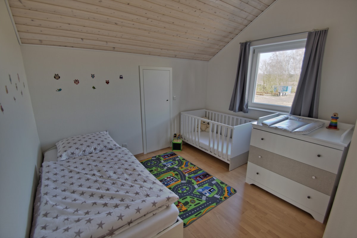 Chambre pour enfants avec un lit superposé, un lit bébé et une commode à langer à l'étage