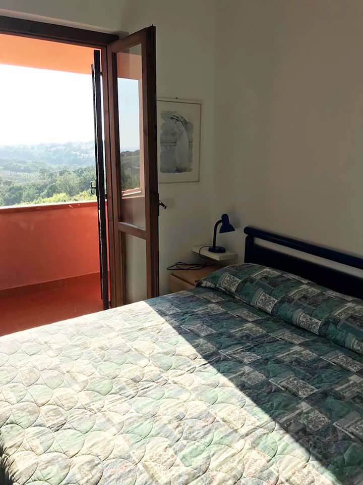 Двойна спалня с тераса и панорамна гледка към морето в далечината.