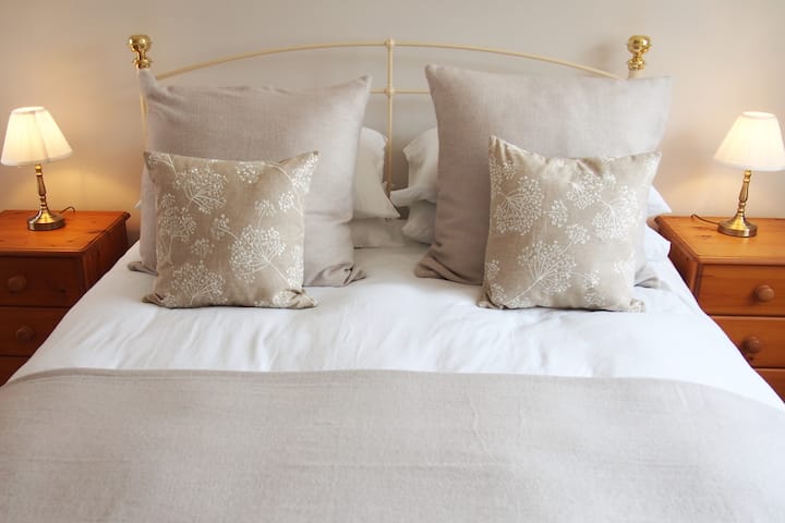 Dormitorio en la planta baja con cama tamaño king y baño separado con ducha, con vistas al jardín. Espacio para colgar, secador de pelo y toallas y sábanas adicionales si es necesario. 