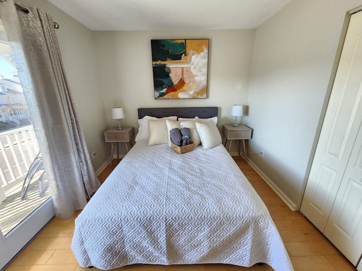 Bedroom 3 with a queen size bed with storage, closet, ceiling fan and TV. This room also has sliding doors to go out to a balcony on the front side of the house. 