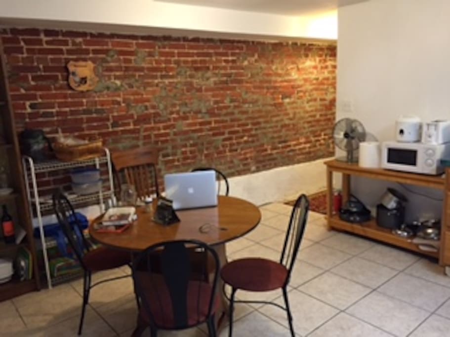 Dining area with the exposed brick wall in the background leading to the main hall in the basement.