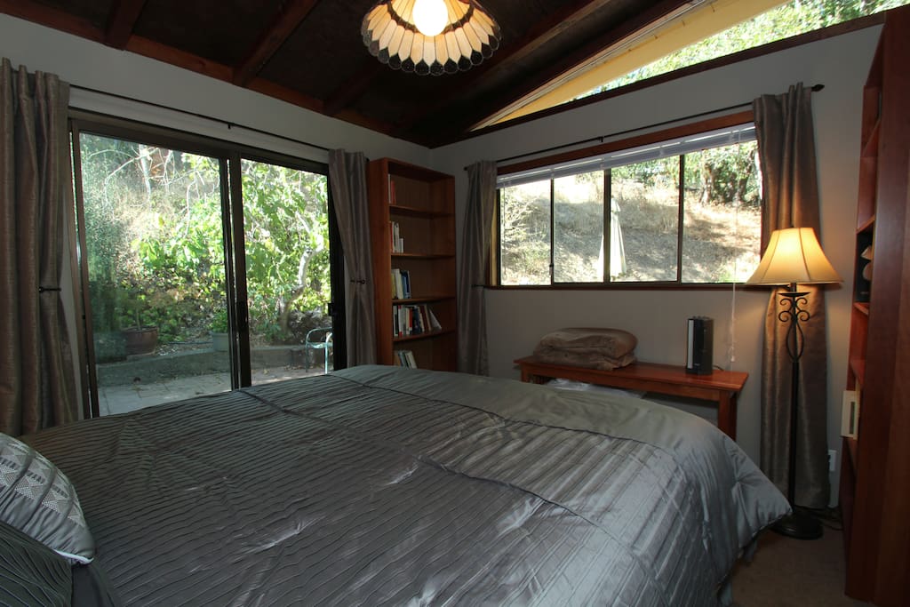 King bed - sliding glass door to small patio – double windows looking out to trees and large patio.
