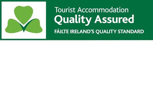 The image displays the Fáilte Ireland Quality Standard logo, featuring a green background with white text and a stylized green shamrock symbol indicating quality assurance for tourist accommodations.
