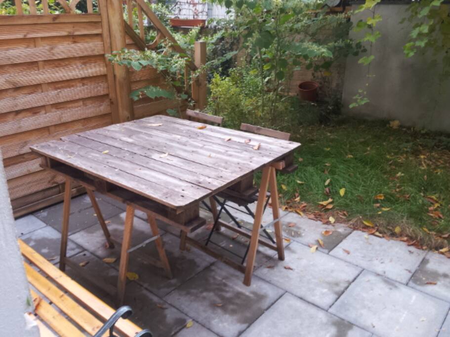 Private garden in the courtyard with room table, bench, and chairs.