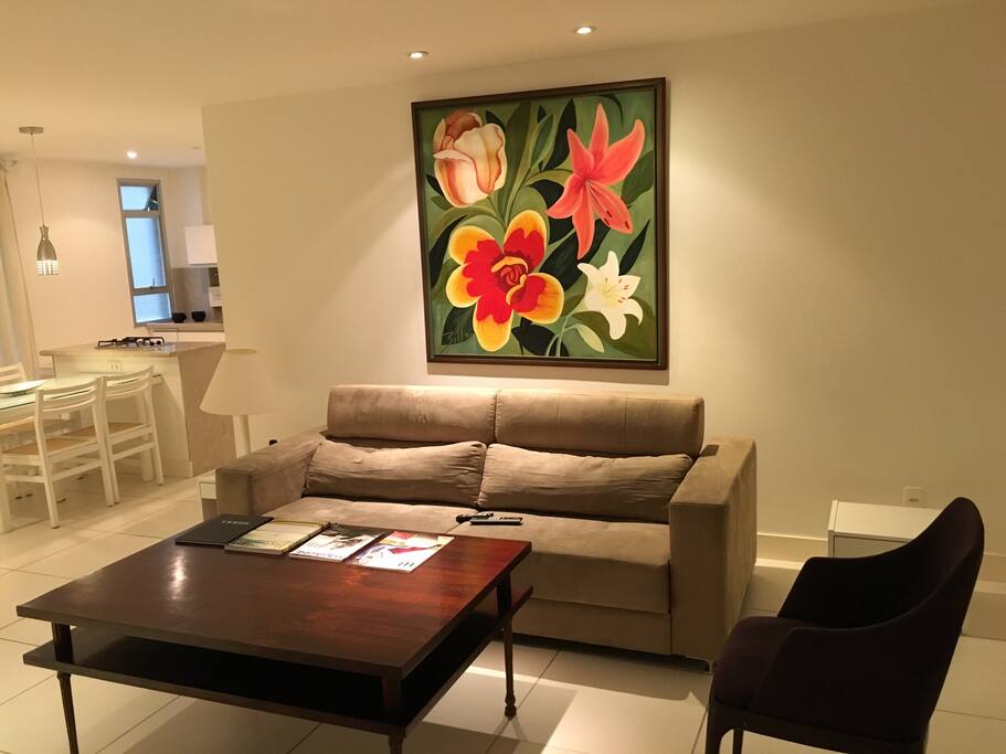 Sala com sofá reclinado, poltrona, telefone e tv a cabo.