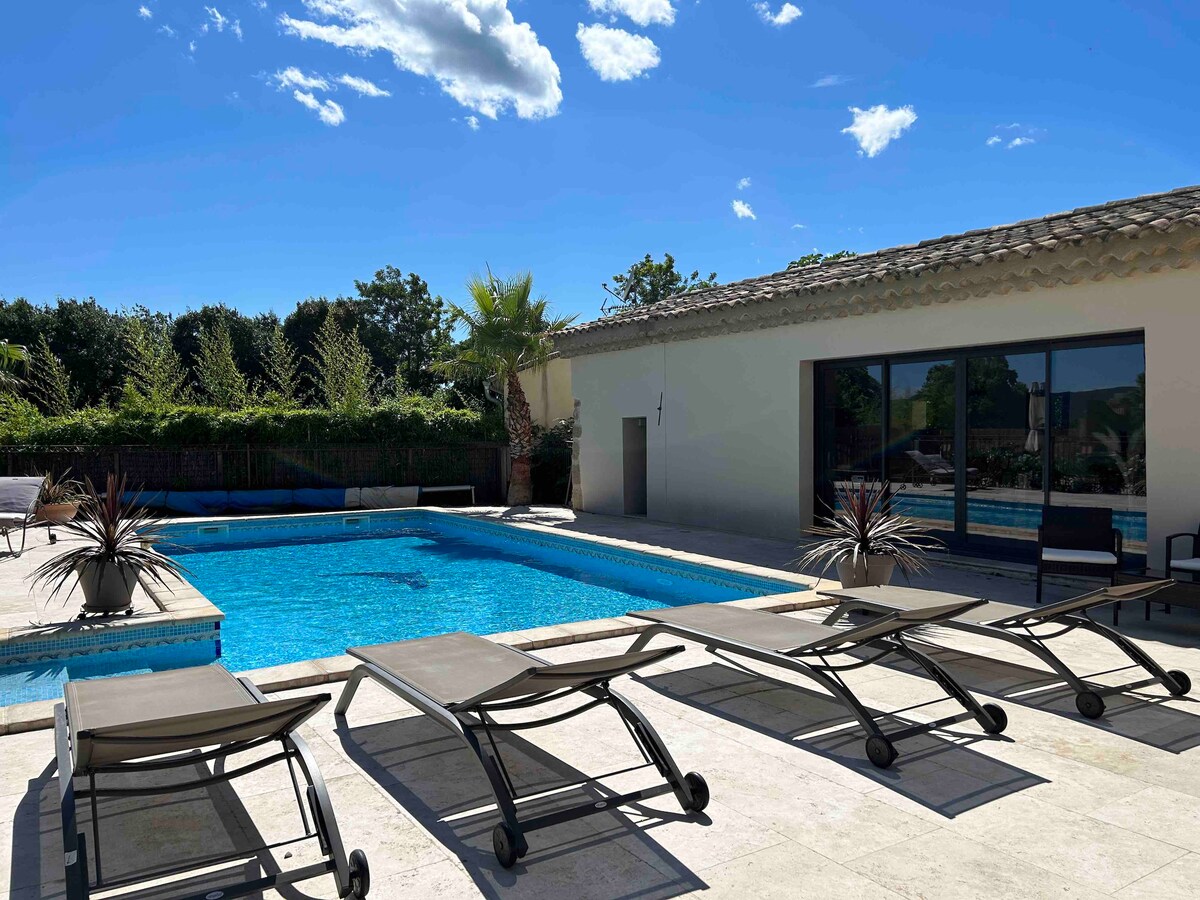 A pool area is showcased, featuring an inviting swimming pool surrounded by multiple lounge chairs and tropical plants. Natural light reflects off the water, while a modern building with large glass doors is visible in the background.