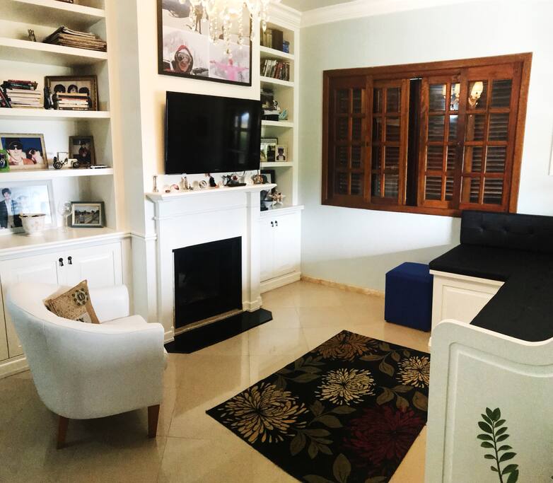 Sala de estar com lareira, televisão, sofá para 4-5 pessoas, poltrona e espaço bem arejado.