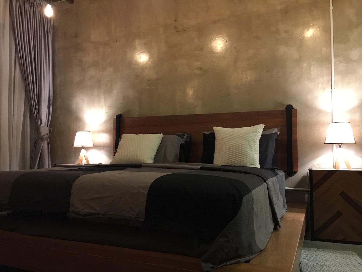 Glavna spavaća soba s bračnim krevetom Nyatoh i čeličnim krevetom i stolićima po mjeri.